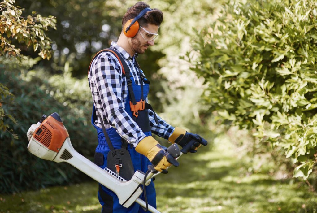 Man with weedwacker cutting the grass
